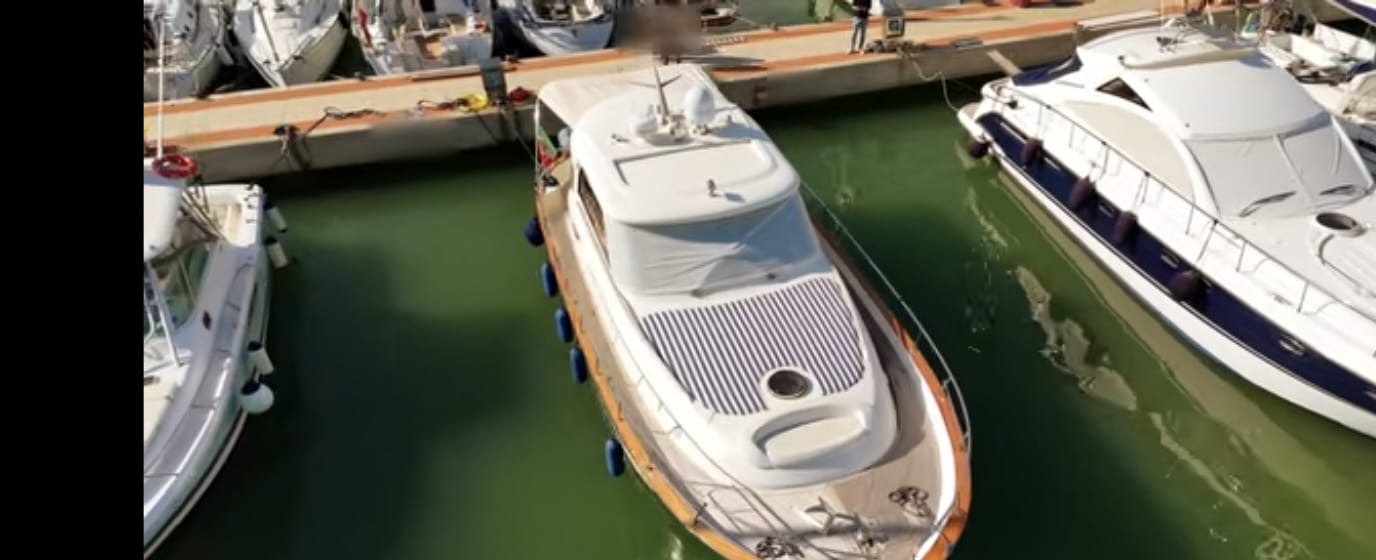 La barca ormeggiata tra gli yacht del porto